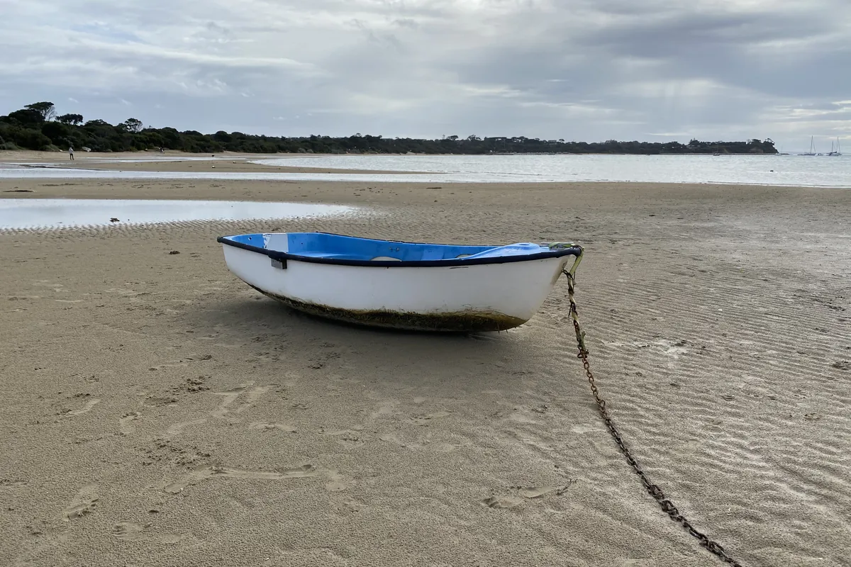 A small dinghy resting on the sand at low tide on Port Phillip Bay near Blairgowrie
