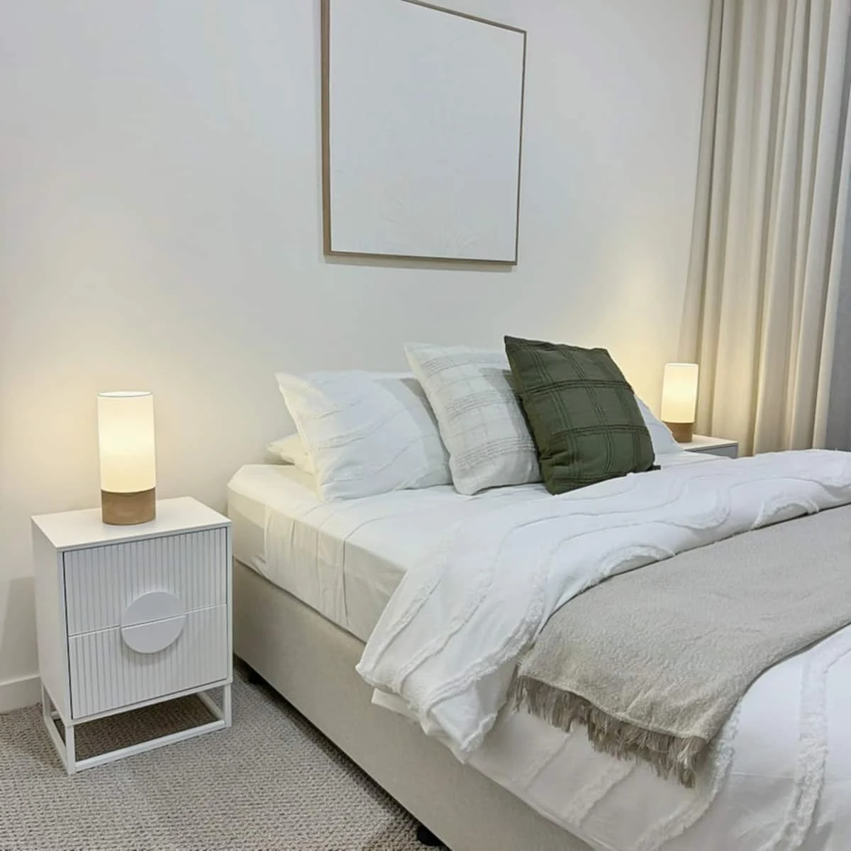 Bedroom with soft white linen and olive cushions